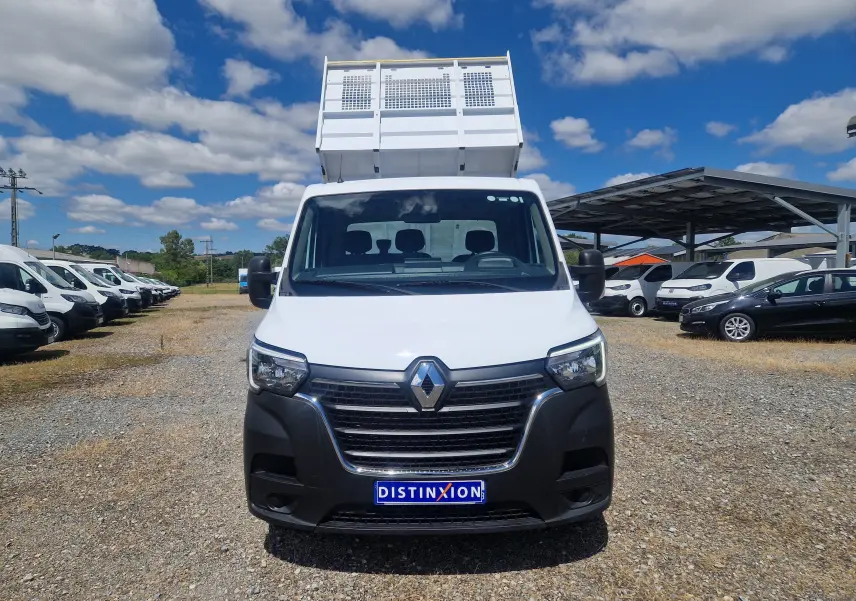 Vue frontale d’un Renault Master Châssis Cabine blanc avec benne surélevée, stationné sur un terrain extérieur sous ciel bleu.