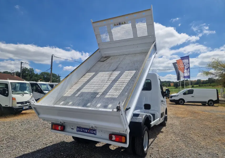 Renault Master Benne blanche vue 3/4 arrière avec benne relevée et roues jumelées sur terrain extérieur.