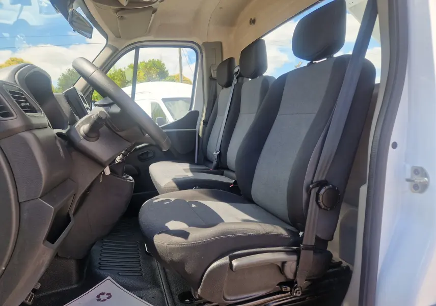 Vue intérieure côté conducteur du Renault Master Châssis Cabine blanc 2024, montrant les sièges tissu gris et noir, volant et tableau de bord.