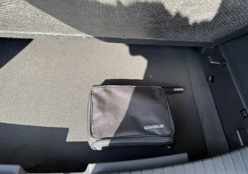 Coffre du Dacia Duster blanc glacier 2026, vue plongeante sur un sac noir posé au sol du coffre.