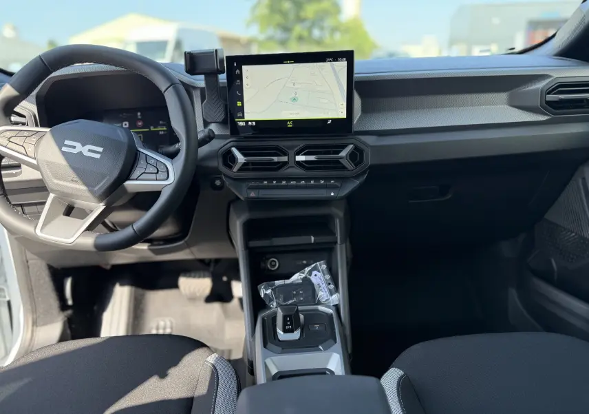 Vue intérieure frontale du tableau de bord du Dacia Duster Hybrid 155 Journey avec écran tactile et volant multifonction noir.