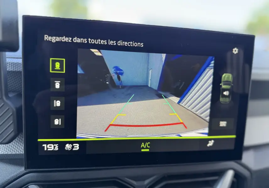 Écran intérieur du Dacia Duster Hybrid 155 Journey montrant la caméra de recul avec guidage coloré, tableau de bord noir.