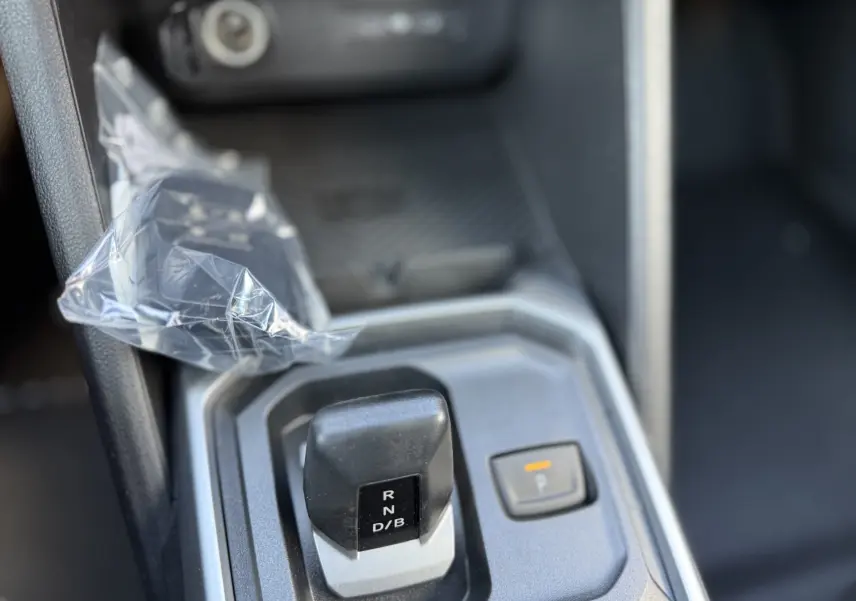 Gros plan sur le levier de vitesses automatique et bouton de parking électronique dans l’habitacle du Dacia Duster blanc glacier.