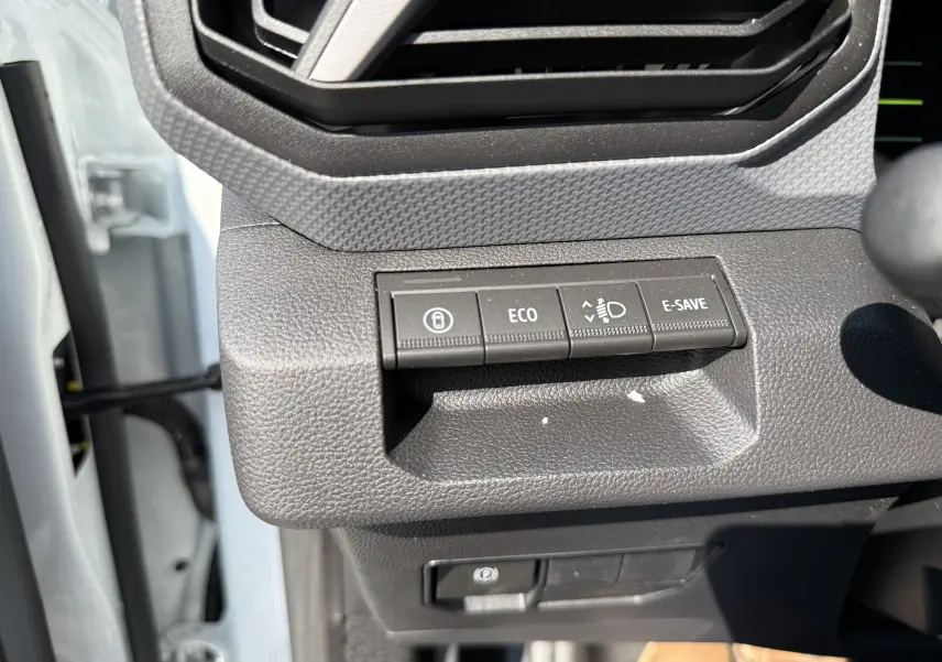 Gros plan sur les boutons de commande à gauche du volant du Dacia Duster blanc Glacier, avec touches ECO et E-SAVE visibles.