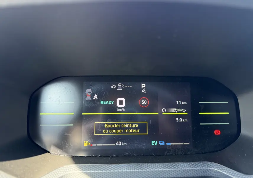 Affichage numérique du tableau de bord du Dacia Duster Hybrid 155 Journey montrant la vitesse à zéro et alertes de sécurité.