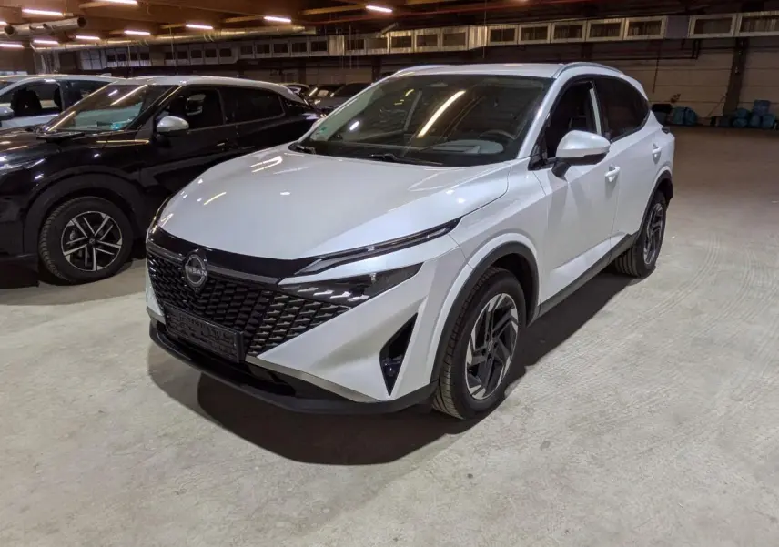 Nissan Qashqai blanc nacré vu en 3/4 avant droit, avec calandre noire et jantes alliage 18 pouces.