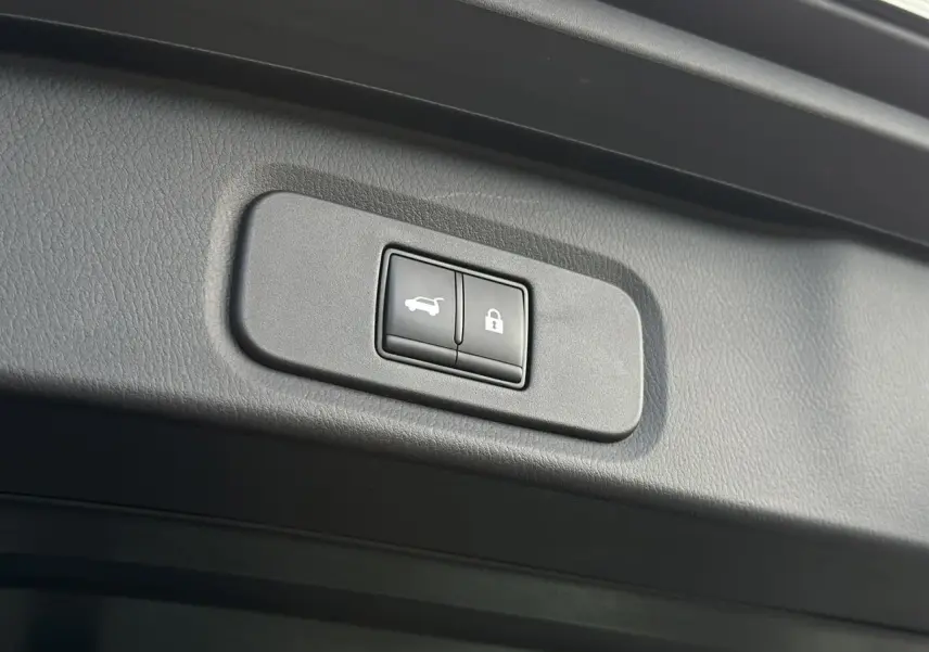 Gros plan sur les boutons de hayon électrique et verrouillage dans le coffre du Nissan Qashqai blanc nacré 2025.
