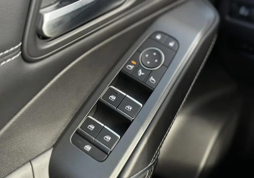 Gros plan sur les commandes des vitres électriques côté conducteur du Nissan Qashqai 2025, finition noire avec surpiqûres blanches.