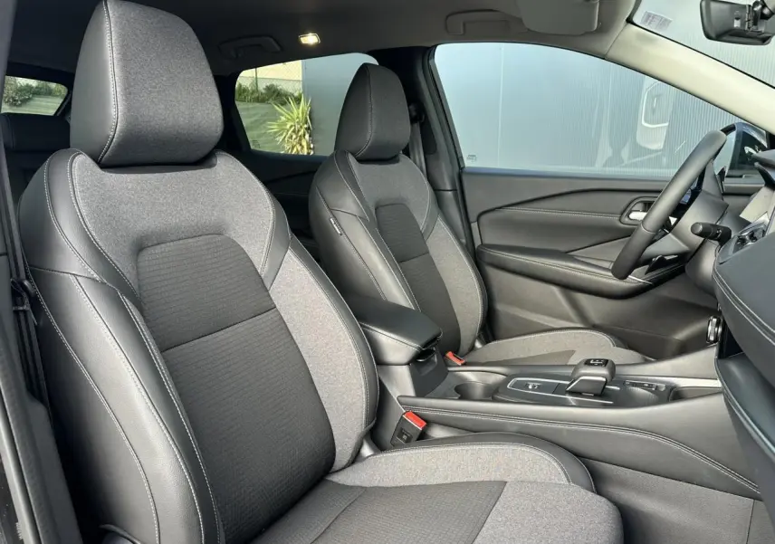 Vue intérieure côté droit des sièges avant en sellerie mixte gris et noir du Nissan Qashqai 2025 blanc nacré.