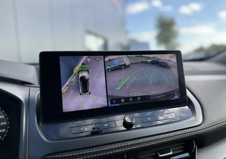 Écran central du Nissan Qashqai blanc nacré montrant la caméra de recul et la vue à 360° du stationnement.