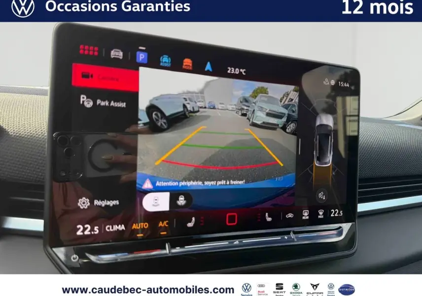Vue intérieure de l'écran tactile du Volkswagen T-Roc bleu montrant l'assistance au stationnement avec caméra de recul.