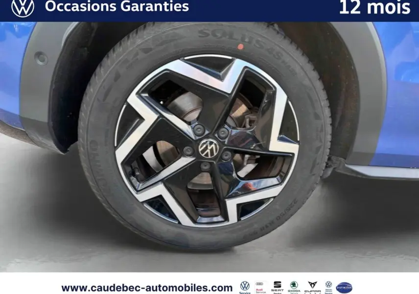 Gros plan sur la jante alliage Coventry noire et brillante du côté gauche d’un Volkswagen T-Roc bleu métallisé.