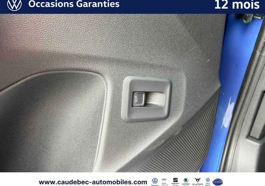 Détail du bouton d'ouverture du coffre sur la porte côté gauche d'un Volkswagen T-Roc bleu métallisé.