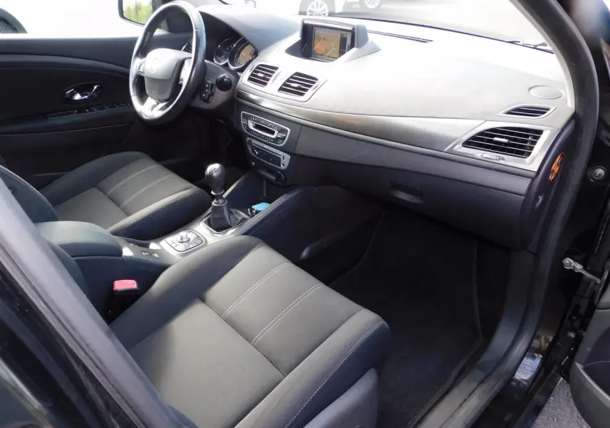 Vue intérieure côté conducteur de la Renault Mégane noire, montrant le tableau de bord avec GPS et la console centrale.