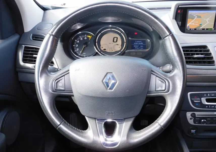 Vue rapprochée du volant Renault Megane 2015 avec tableau de bord numérique et écran GPS intégré sur la droite.