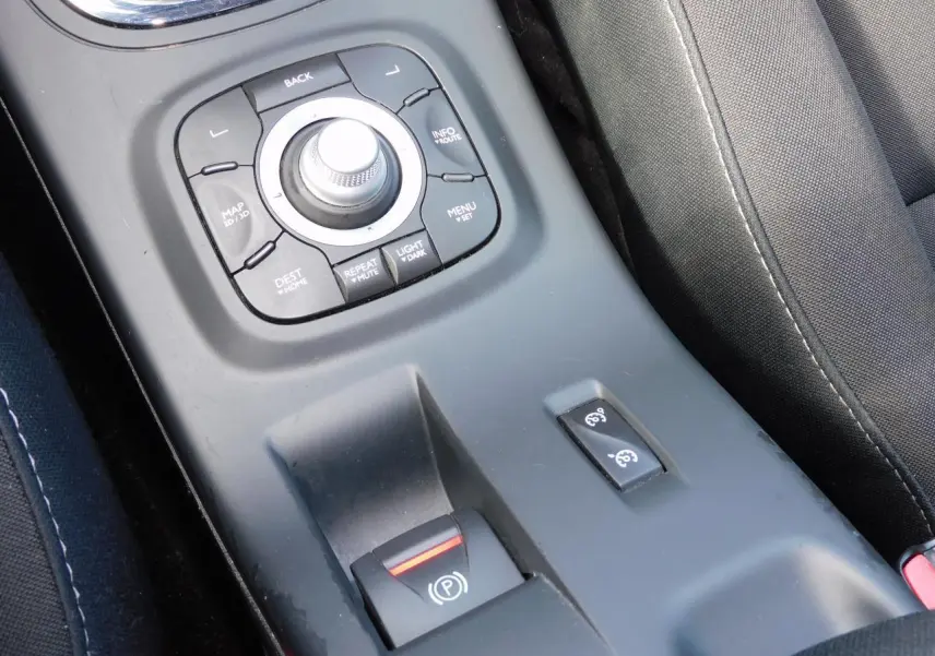 Gros plan sur la console centrale noire de la Renault Mégane 2015, montrant le frein de parking assisté et commandes GPS.