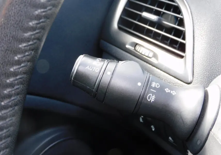 Gros plan sur la commande des feux noirs à gauche du volant dans l'habitacle de la Renault Mégane 2015.