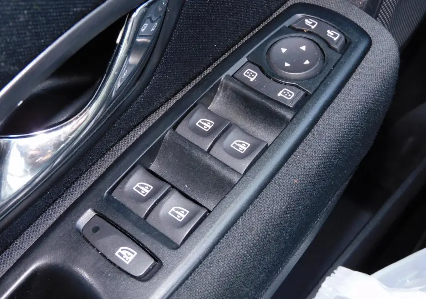 Gros plan sur les commandes de lève-vitres et rétroviseurs côté conducteur d'une Renault Mégane noire de 2015.