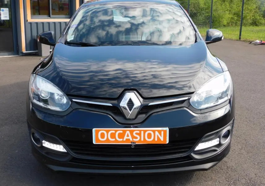 Vue avant d'une Renault Mégane noire 2015 avec phares allumés et plaque orange "OCCASION" visible.