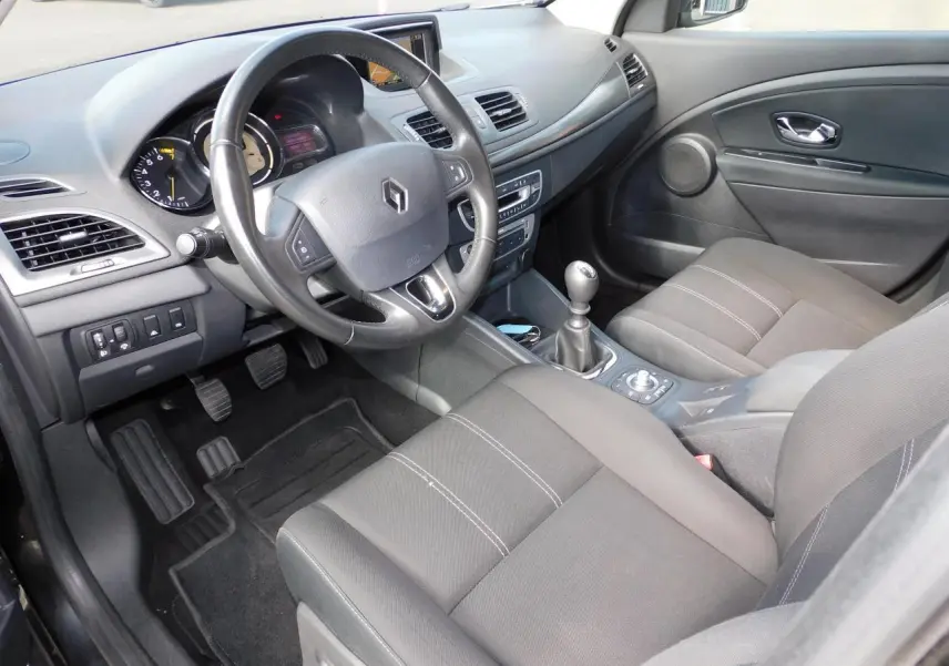 Vue intérieure côté conducteur de la Renault Mégane noire 2015 avec volant multifonction et boîte manuelle.