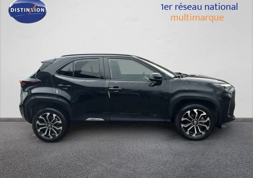 Profil côté gauche d'un Toyota Yaris Cross 116h Design noir 2023 avec jantes bi-ton et lignes robustes.