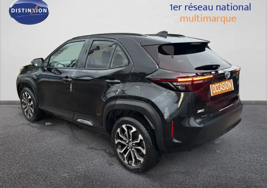 Toyota Yaris Cross 116h Design noir vue 3/4 arrière droit avec jantes bi-ton et feux arrière allumés.