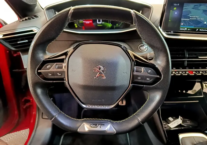 Vue rapprochée du volant cuir GT Line de la Peugeot 208 rouge 2020 avec tableau de bord numérique et écran tactile.