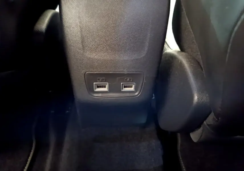 Prise double USB arrière intégrée au dossier central noir de la Peugeot 208 GT Line rouge, vue rapprochée intérieure.