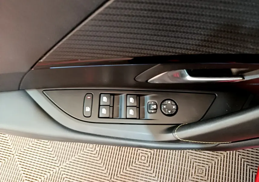 Gros plan sur la commande des vitres côté conducteur de la Peugeot 208 GT Line rouge, avec poignée et bouton de verrouillage.