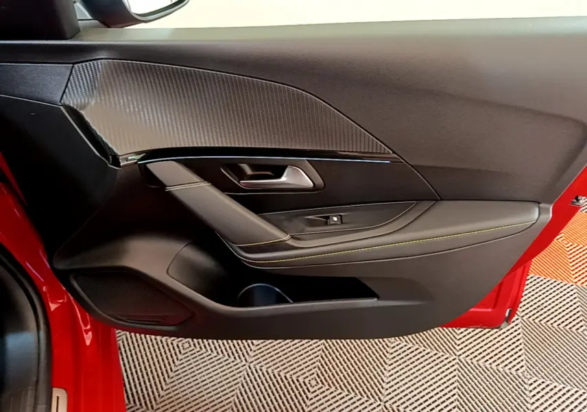 Détail de la porte côté gauche rouge du Peugeot 208 GT Line 2020 avec surpiqûres jaunes et insert carbone.