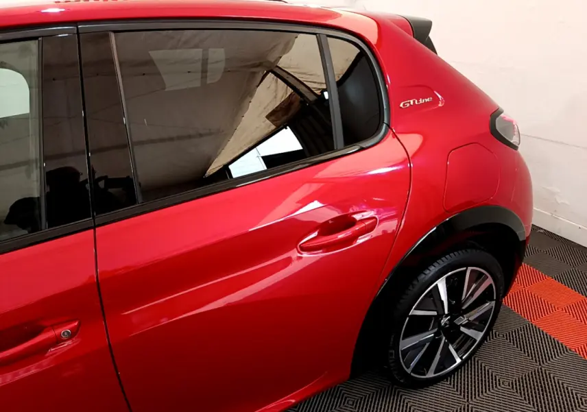 Vue latérale droite sur l'arrière d'une Peugeot 208 GT Line rouge avec jante alliage et logo GT Line visible.