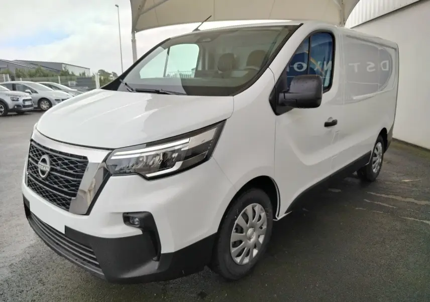 Nissan Primastar blanc en vue 3/4 avant droit, fourgon utilitaire avec calandre noire et jantes acier.