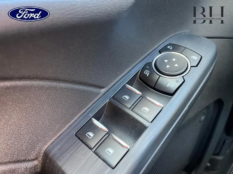 Gros plan sur les commandes de lève-vitres et rétroviseurs côté conducteur du Ford Kuga gris, avec finition texturée noire.