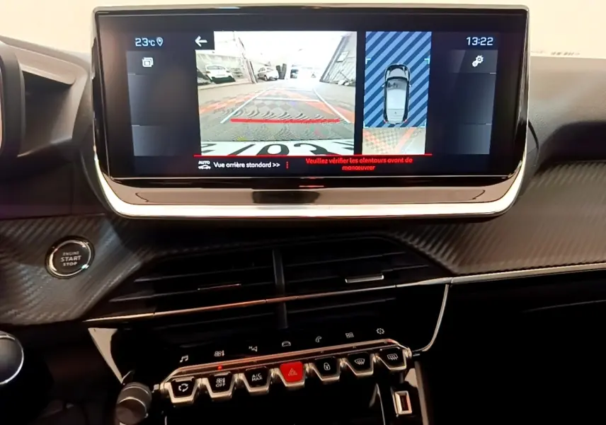Vue rapprochée de l’écran tactile central affichant la caméra de recul dans l’habitacle noir d’une Peugeot 208 blanche.