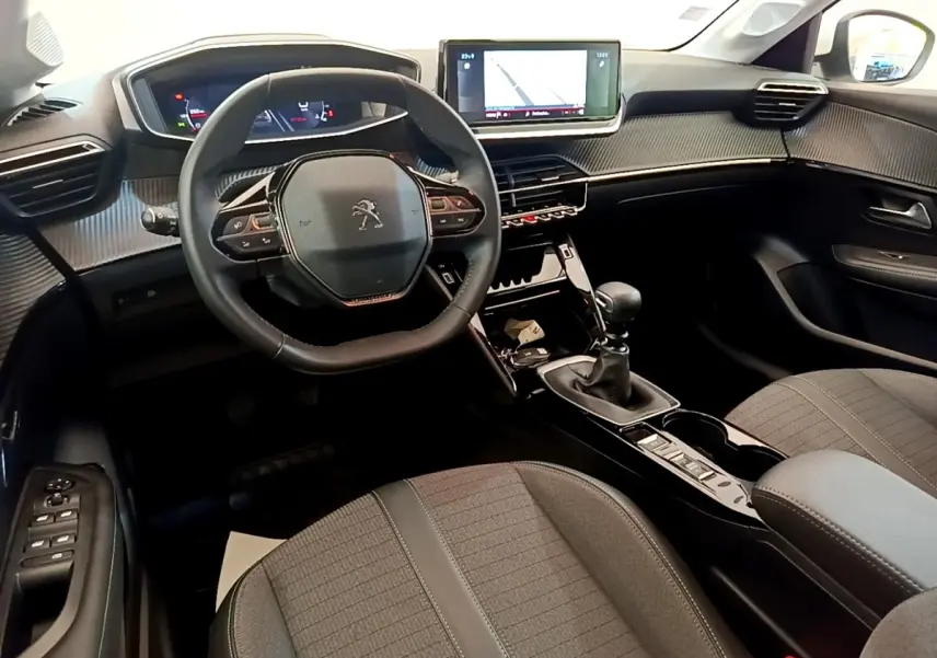 Vue intérieure avant de la Peugeot 208 blanche, avec volant cuir, écran tactile 10 pouces et boîte manuelle.