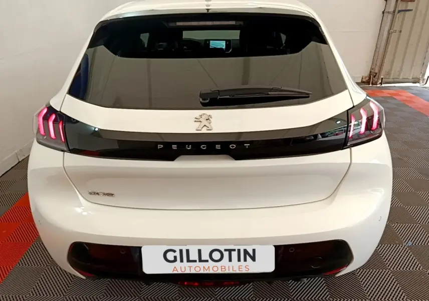 Vue arrière d'une Peugeot 208 blanche avec feux arrière LED en forme de griffes et logo Peugeot noir brillant.