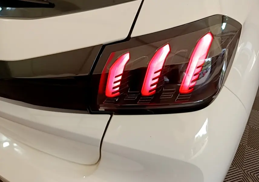 Gros plan sur le feu arrière droit rouge de la Peugeot 208 blanche PureTech 100 S&S Allure Business de 2021.