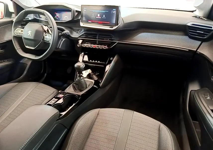 Vue intérieure avant droite du Peugeot 208 PureTech 100 S&S Allure Business 2021 avec tableau de bord noir et écran tactile 10 pouces.