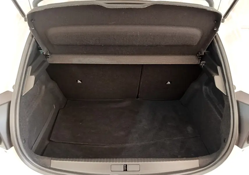 Coffre ouvert vu de l'arrière d'une Peugeot 208 blanche, montrant un espace de chargement propre et vide.