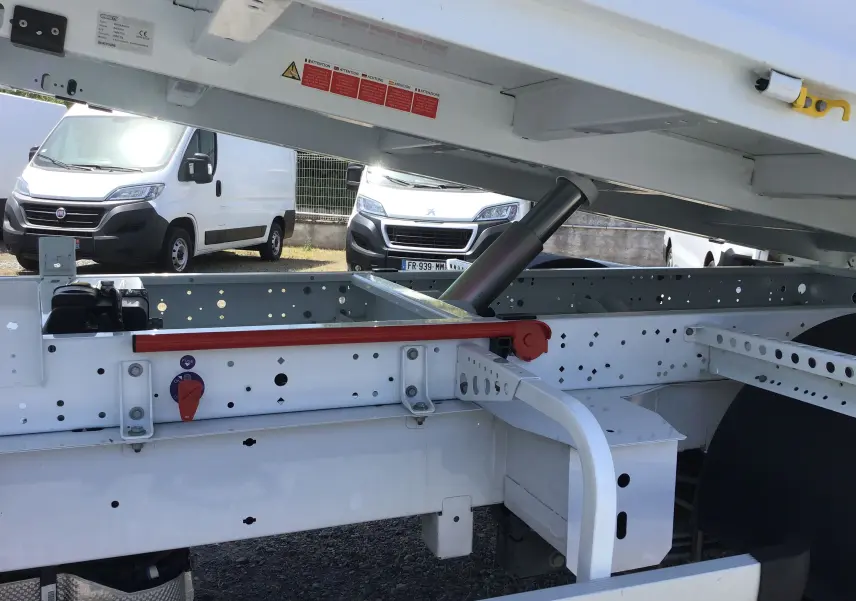 Détail sous la benne relevée du Renault Master Châssis Cabine blanc, montrant le vérin hydraulique et la structure métallique.