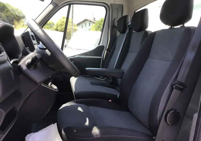 Vue intérieure côté conducteur du Renault Master Châssis Cabine 2024, montrant les sièges gris foncé et le volant noir.