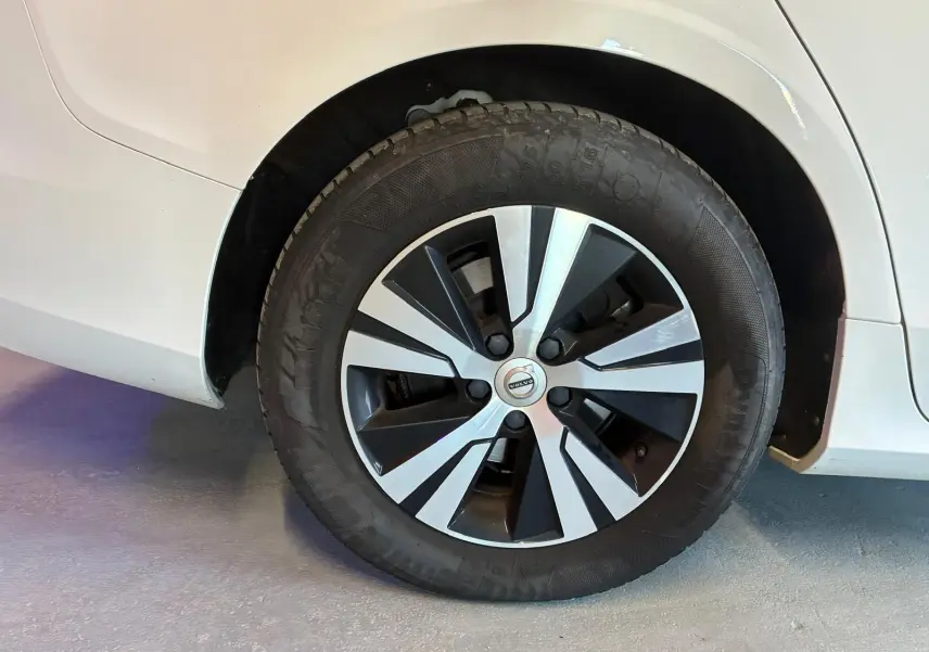 Gros plan sur la roue avant droite d'une Volvo V60 blanche, jante alliage bicolore au design moderne.