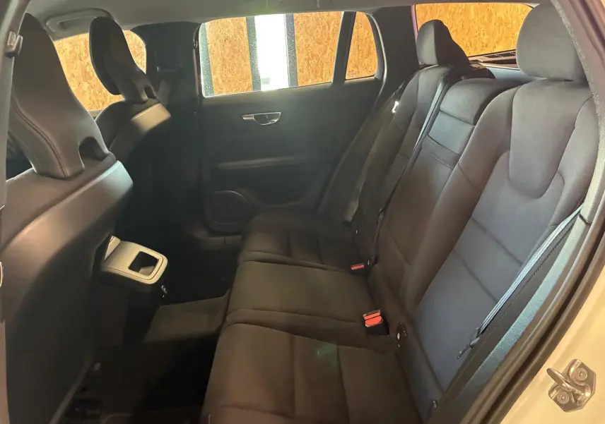 Vue intérieure côté droit des sièges arrière noirs en tissu d'une Volvo V60 D3 2020 blanche avec portes ouvertes.