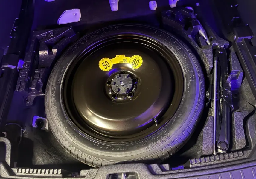 Vue plongeante sur la roue de secours noire et les outils de coffre du Volvo V60 blanc, version D3 2020.