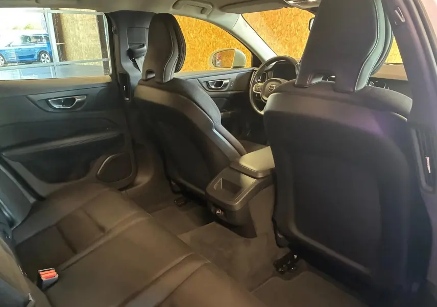 Vue intérieure arrière côté gauche d’un Volvo V60 D3 2020 avec sièges noirs en tissu et tableau de bord visible.