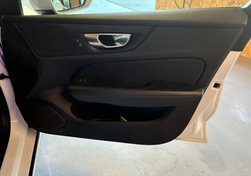 Vue intérieure de la porte avant gauche noire avec poignée chromée d'une Volvo V60 D3 blanche de 2020.