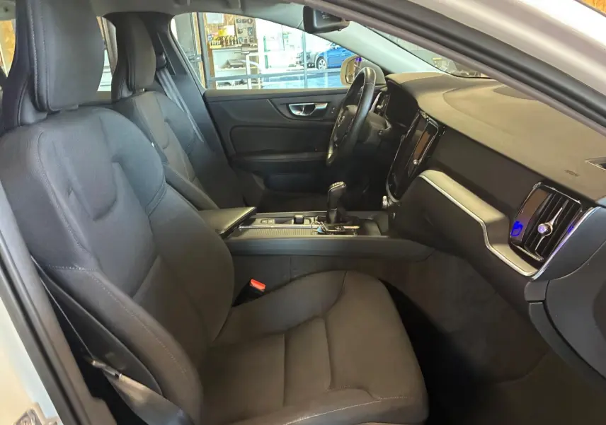 Vue intérieure côté conducteur de la Volvo V60 D3 2020, sièges tissu noir et tableau de bord moderne.