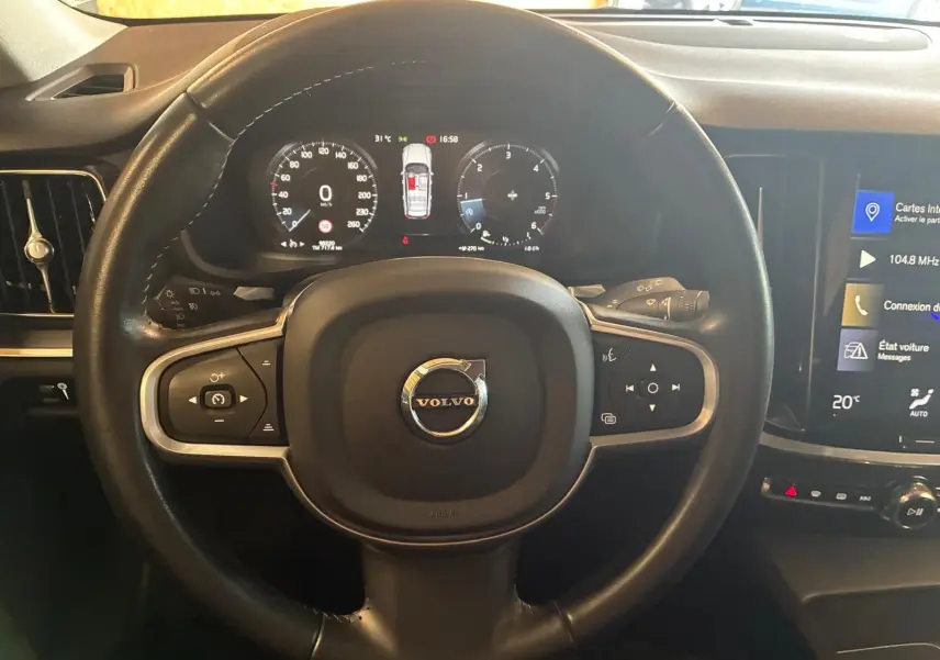 Vue rapprochée du volant noir de la Volvo V60 D3 2020 avec tableau de bord digital et écran tactile central.