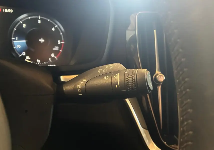Gros plan sur la commande d’essuie-glace à gauche du volant dans l’habitacle noir du Volvo V60 blanc de 2020.