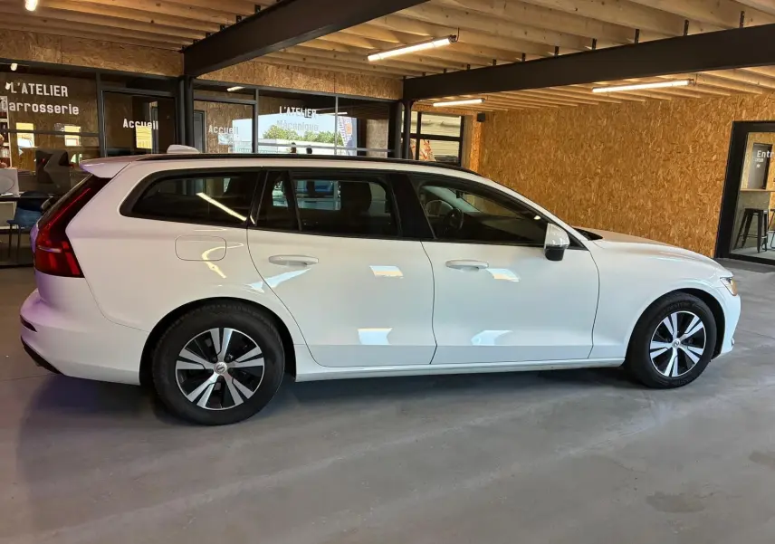 Vue de profil côté gauche d'un Volvo V60 blanc de 2020, break 5 portes avec jantes alliage et intérieur noir visible.